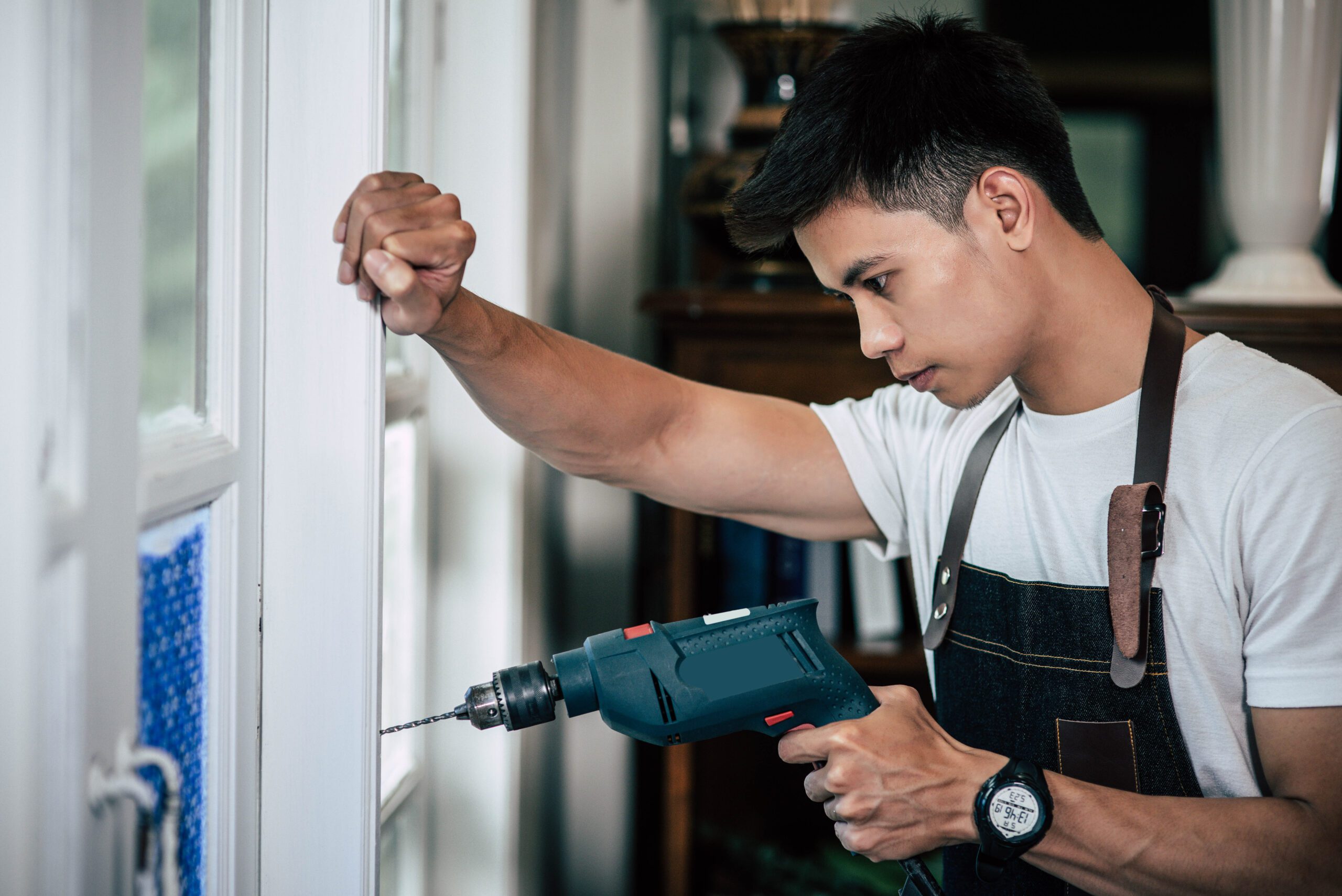 The carpenter holds the drill and drills the window.